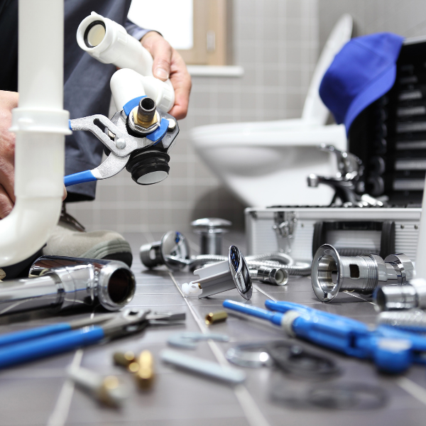 Plumbing fixtures on bathroom floor being repaired by plumber