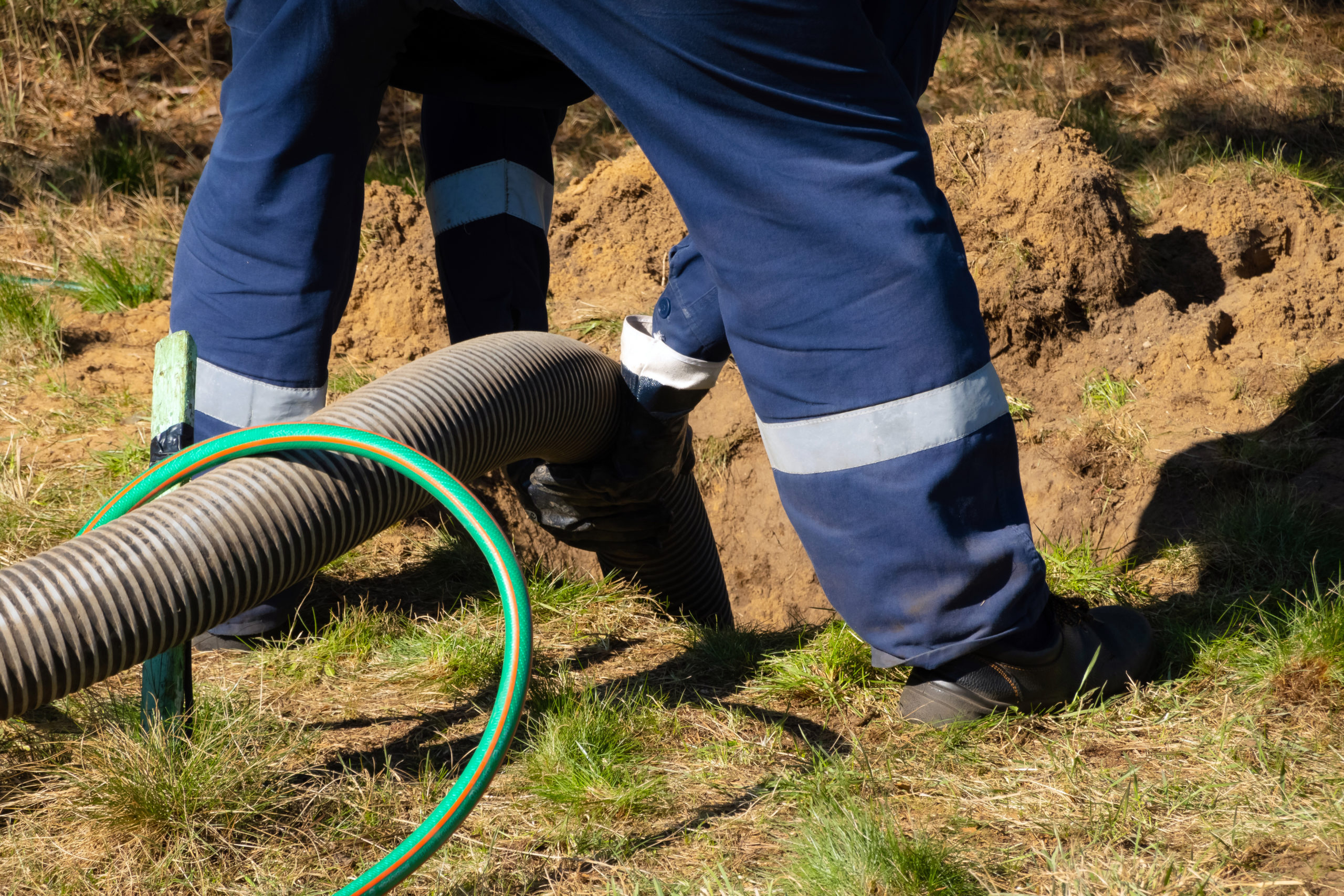 Man worker holding pipe, providing sewer cleaning service outdoor.