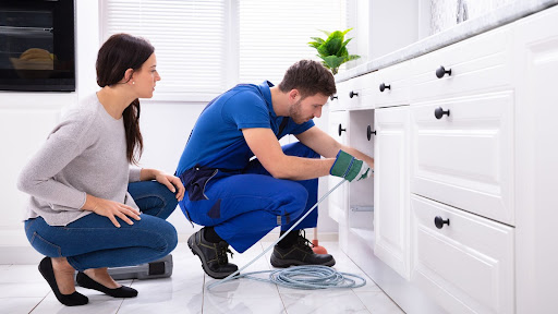 Plumbing technician hydrojetting under sink